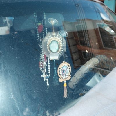 Rosaries and religious medallions hanging behind a dusty windscreen